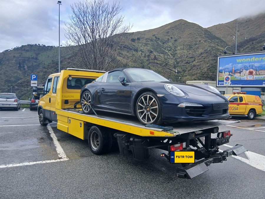Yellow vehicle recovery truck transporting a Porsche